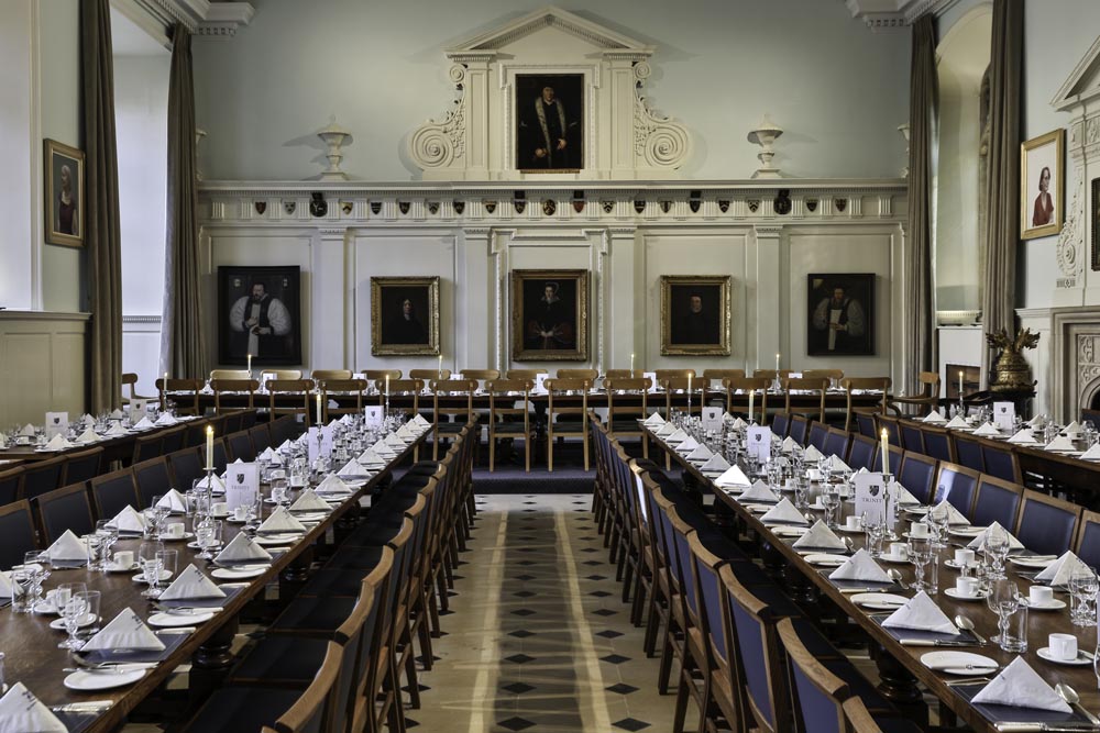 The dining room at Trinity College Oxford, it shows the tables set for dinner and a stunning room that has been updated by Original Field of Architecture Oxford.
